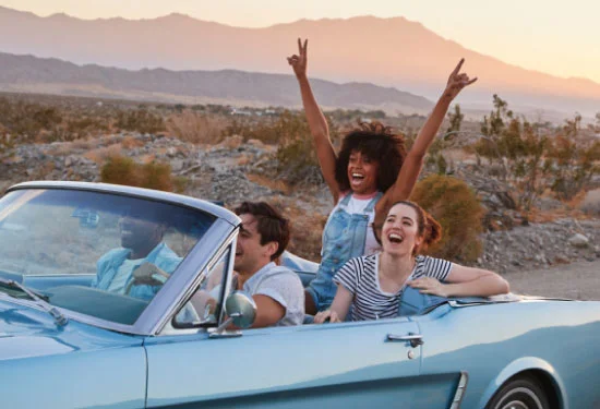 group of friends on road trip in classic convertible car