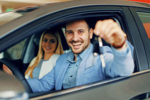 Couple holding up new keys to a new car