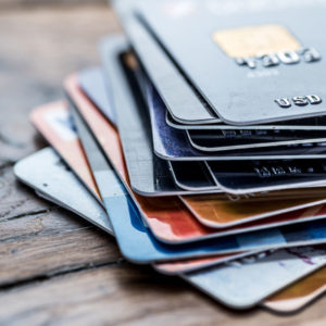 Stack of colorful credit and debit cards on a wooden table.