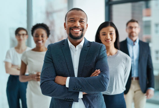 A diverse group of people stand smiling in an office.