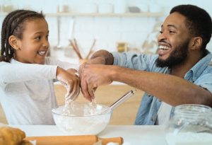 Father and daughter making cookies at the kitchen.