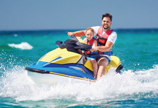 Father ans son having fun on a jet ski in the water smiling