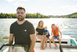 Family boating together on lake, with mother, father and two children wearing life-jackets