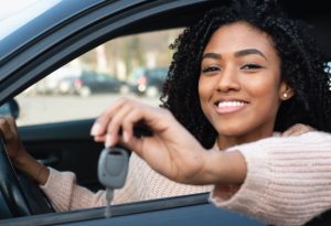 african american young adult holding keys to her newly purchased car