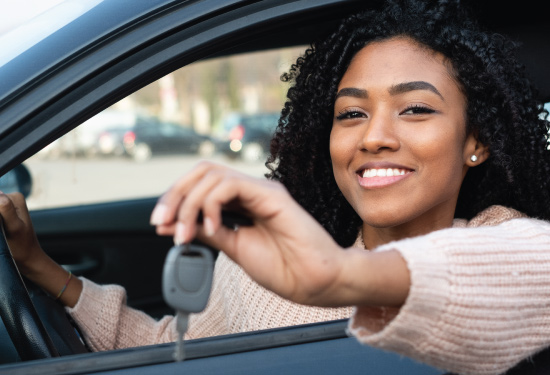 african american young adult holding keys to her newly purchased car