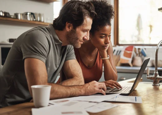 adult couple in kitchen looking at laptop planning a major purchase