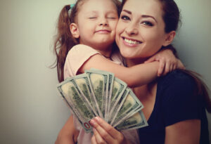 A mom holds her young child and money.