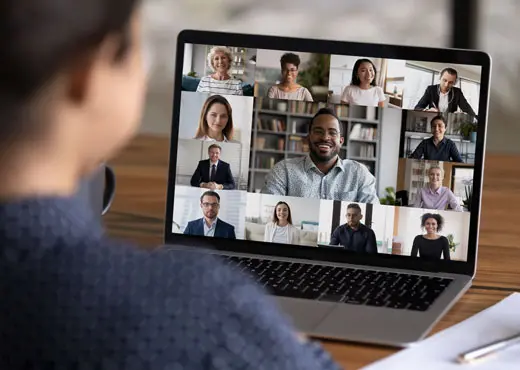 A person views an online virtual meeting on a laptop screen.