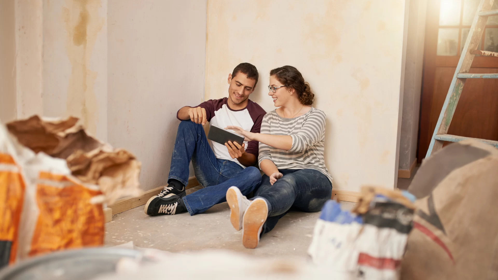Man and a women talking to each other while sitting on the floor of their home during a home remodel project.