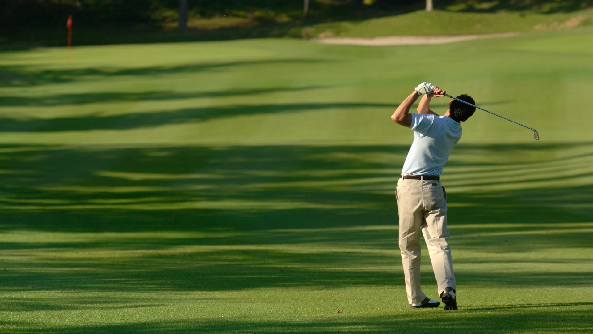Man swinging a golf club on a golf course.